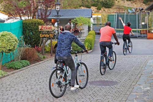 three people riding bikes down a street at Potter's Place by Ardenne Places in Theux
