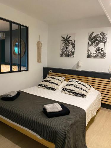 a bedroom with a large bed with black and white pillows at Centre & plage - T2 cosy avec terrasse & jardin in Saint-Gilles les Bains
