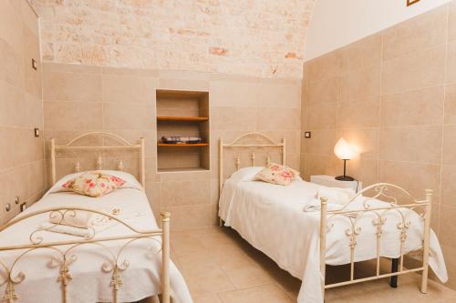 2 Einzelbetten in einem Zimmer mit Ziegelwand in der Unterkunft La Casetta Antica in Noci