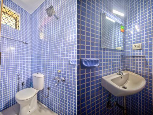 a blue tiled bathroom with a toilet and a sink at Hidden Caves Inn in Baga