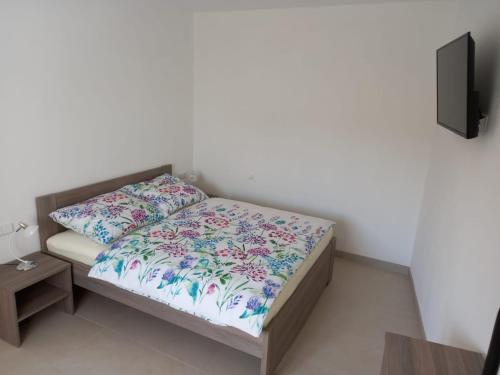 Penzion U strejčků في فاسيلي ناد لوزنيتسا،: غرفة نوم صغيرة مع سرير مع وسادة وتلفزيون
