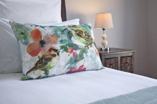 a bed with a pillow with a flower pattern on it at Sunbird Cottage in Somerset West
