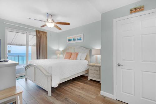 a white bedroom with a bed and a ceiling fan at Sterling Reef 102 in Panama City Beach