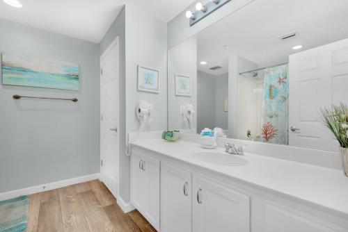 a white bathroom with a sink and a mirror at Sterling Reef 102 in Panama City Beach