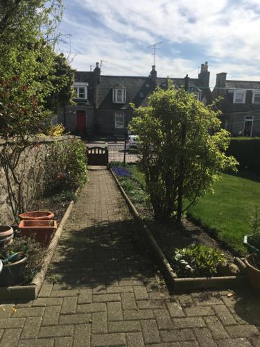 a garden with a brick walkway with a tree at Roselodge Guest House in Aberdeen