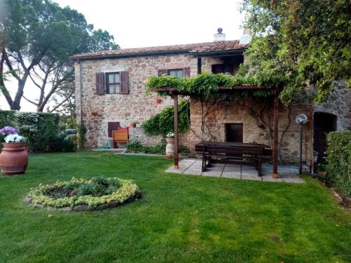 um jardim com um banco em frente a uma casa de pedra em Agriturismo “Sterrati” em Valpiana