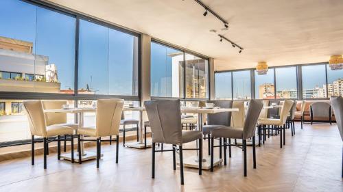 a restaurant with tables and chairs and large windows at Hotel Les Ambassadeurs in Casablanca