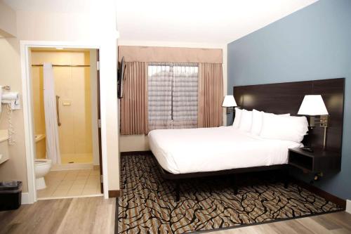 a hotel room with a bed and a bathroom at Baymont by Wyndham Jackson/Ridgeland in Jackson