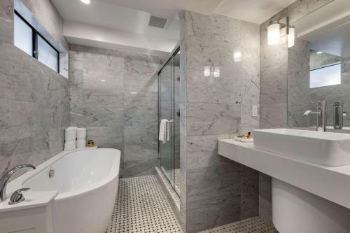 a bathroom with a tub and a sink and a shower at The Encinitan Hotel & Suites in Encinitas