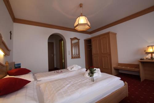 a bedroom with a large white bed with a vase on it at Gast- und Ferienhof Christler in Tux