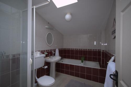 een badkamer met een wastafel, een toilet en een bad bij Lizzys Little Kitchen Town Accommodation in Listowel