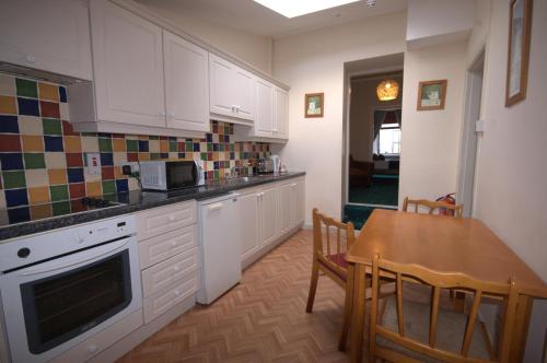 een keuken met witte kasten en een tafel en een eetkamer bij Lizzys Little Kitchen Town Accommodation in Listowel