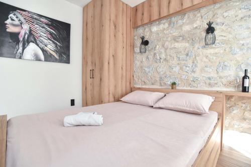 a bedroom with a white bed with a stone wall at Sambra old town apartment in Budva