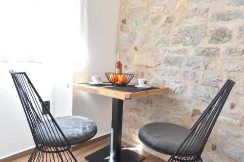 two chairs at a table in a room with a stone wall at Sambra old town apartment in Budva
