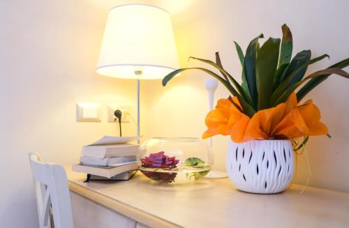 a desk with a vase with a plant and a lamp at Hotel Baglio Di Scopello in Scopello