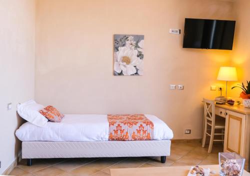 a bedroom with a bed and a desk and a television at Hotel Baglio Di Scopello in Scopello