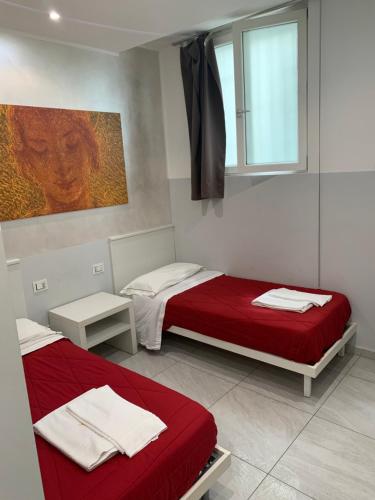 una camera con due letti con lenzuola rosse e una finestra di Picaflor Art & Rooms a Milano