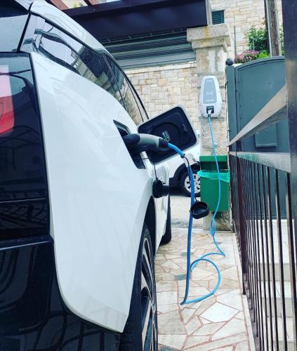 a white car is being charged by an electric charger at Luigi apartments in Dubrovnik