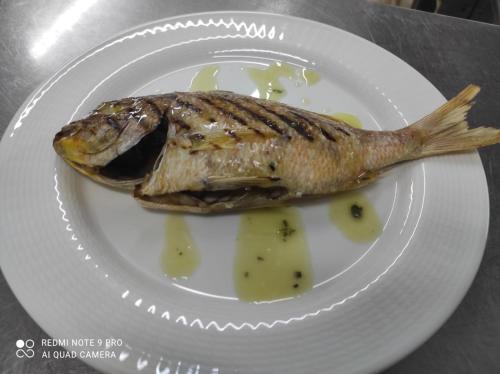 a fish on a white plate on a table at Hotel La Fattoria Sul Mare in Capo Vaticano