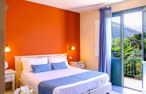 a bedroom with orange walls and a bed and a window at Hotel Baglio Di Scopello in Scopello