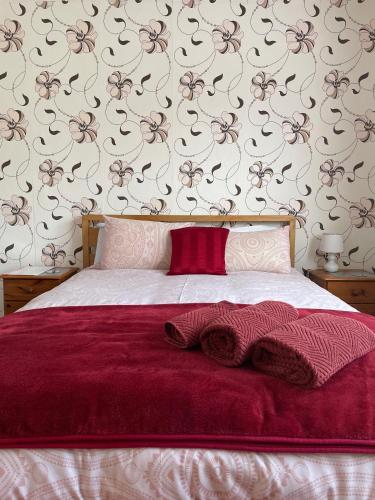 a bedroom with a bed with a red blanket and a wall at Whiteways Guest House in Skegness