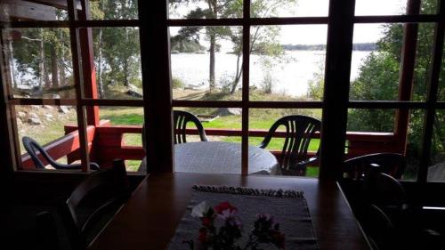 a table and chairs in a room with a large window at Mellangårds stugor - Stockstugan in Föglö