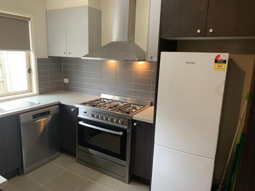 a kitchen with a stove and a white refrigerator at Elmsford Cottage in Warragul