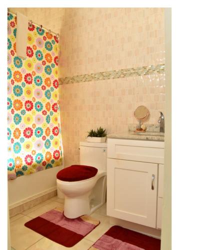 a bathroom with a toilet and a shower curtain at Caribbean estate deluxe 2 in Portmore
