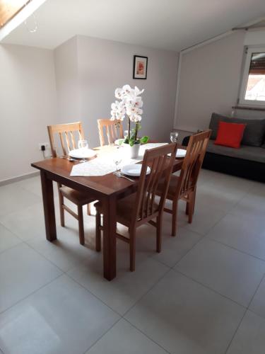 a wooden dining room table with chairs and a vase of flowers at Apartment Juliette in Zadar