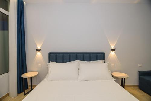 a bedroom with a white bed and two stools at Palm Side Hotel in Vlorë