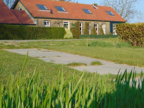 a house with a red roof and a driveway at Polderhuis voor 8-10 personen aan zee in Nieuwvliet