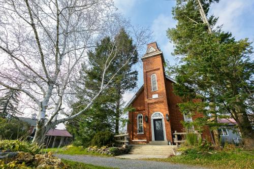 una iglesia de ladrillo rojo con una torre de reloj en The Prince Edward County Church en Belleville