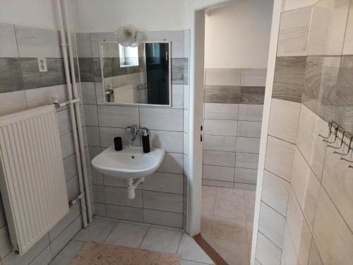 a white bathroom with a sink and a mirror at Penzion MAYKA in Hrabušice