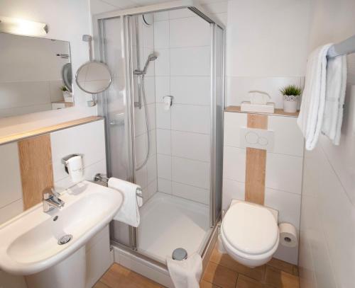 a bathroom with a shower and a toilet and a sink at Landhotel Graf in Schliengen