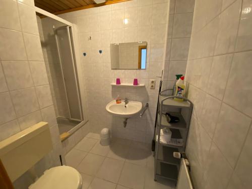 uma casa de banho branca com um lavatório e um WC em Pension Pradler Wohnung 1 em Carolinensiel