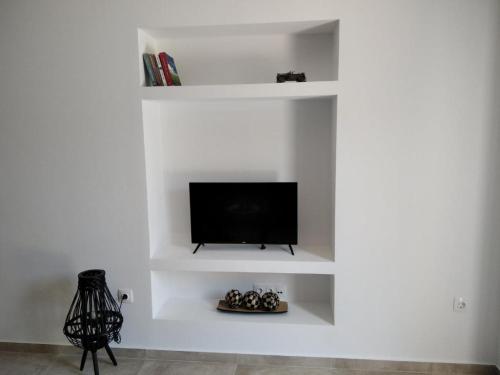 uma sala de estar com televisão em prateleiras brancas em Armonia - Brand new apartment in Ermioni Village em Ermioni