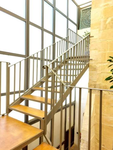 a metal staircase in a room with large windows at Casa Birmula Boutique Hotel in Cospicua