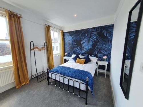 a bedroom with a bed with a blue wall at Stylish City Centre Apartment on the Kings Mile in Canterbury
