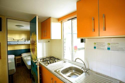 una pequeña cocina con armarios naranjas y fregadero en Italian Holidays Mobile house in Ameglia en Ameglia