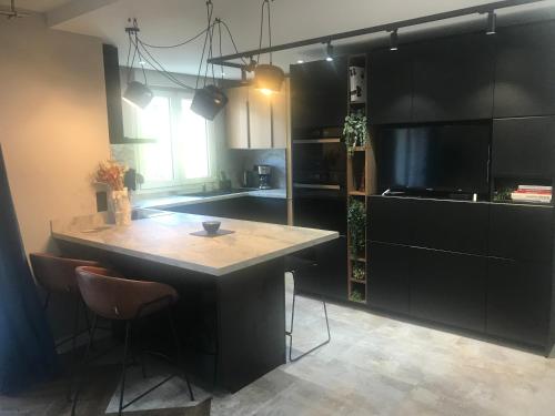 une cuisine avec des armoires noires et un îlot avec des chaises dans l'établissement Nid Douillet - BEL APPARTEMENT avec GARAGE, à Grenoble