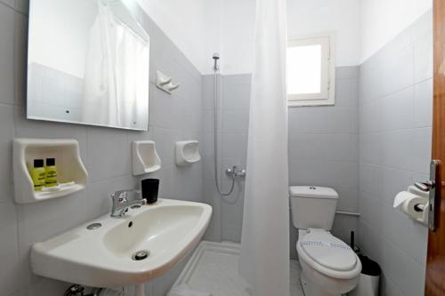 a white bathroom with a sink and a toilet at Lunar Santorini Hotel in Perissa