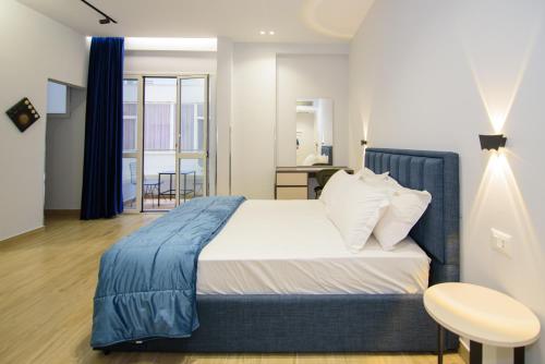 a bedroom with a large bed with a blue blanket at Palm Side Hotel in Vlorë