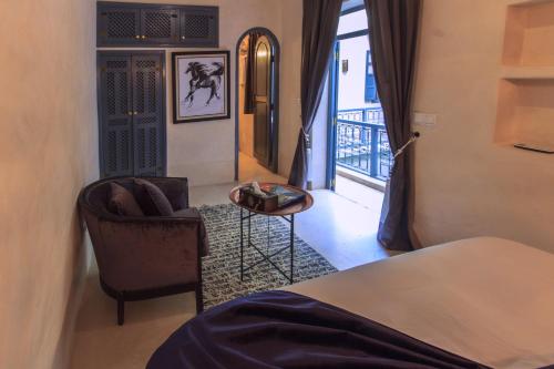 Riad La Porte de l'oasis في مراكش: غرفه فندقيه بسرير وكرسي ونافذه