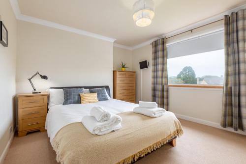 1 dormitorio con 1 cama con toallas en Pipeland Pad - 3 Bed - Parking - Garden en St Andrews