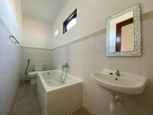 a bathroom with a sink and a toilet and a mirror at Pondok Mimba in Padangbai