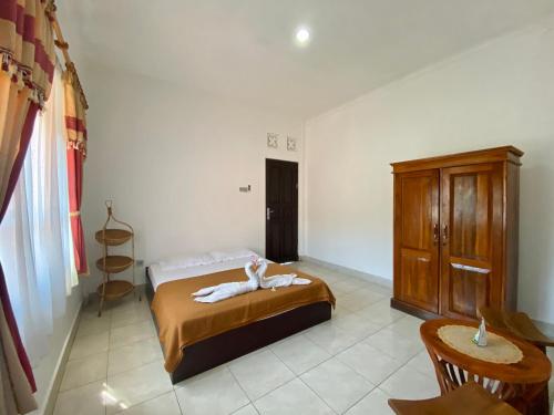 a bedroom with a bed and a wooden cabinet at Pondok Mimba in Padangbai