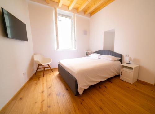 a bedroom with a bed and a television and a chair at Locanda Alberti in Mandello del Lario