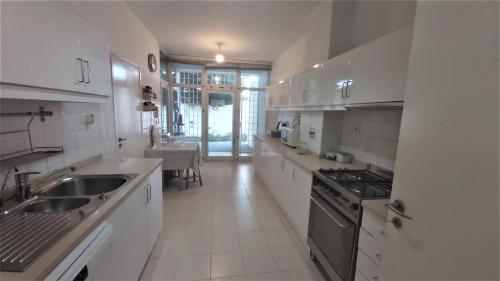 a white kitchen with a sink and a stove at Casa de Gião in Gião