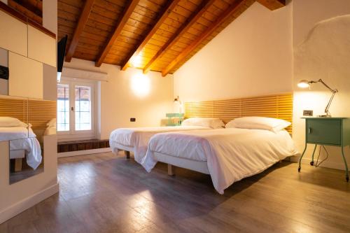 una camera con 2 letti e un soffitto in legno di Locanda Alberti a Mandello del Lario