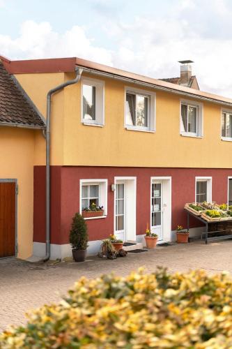 a yellow and red house with potted plants at Gästezimmer/Appartement Familie John in Veitsbronn